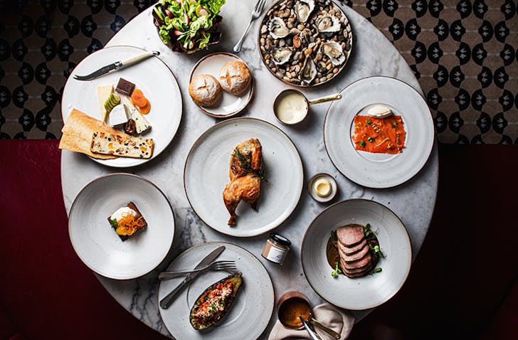 A feast from Hemingway's Wine Room on a round table. A roast chicken studded with truffle sits in the middle as the centrepiece. 