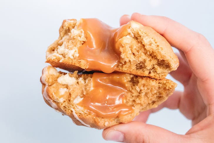 two halves of a cookie stacked together, with caramel oozing out