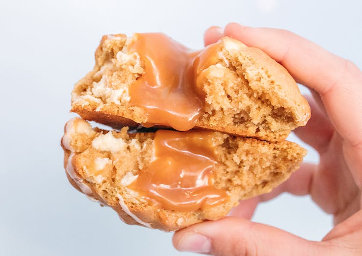 two halves of a cookie stacked together, with caramel oozing out