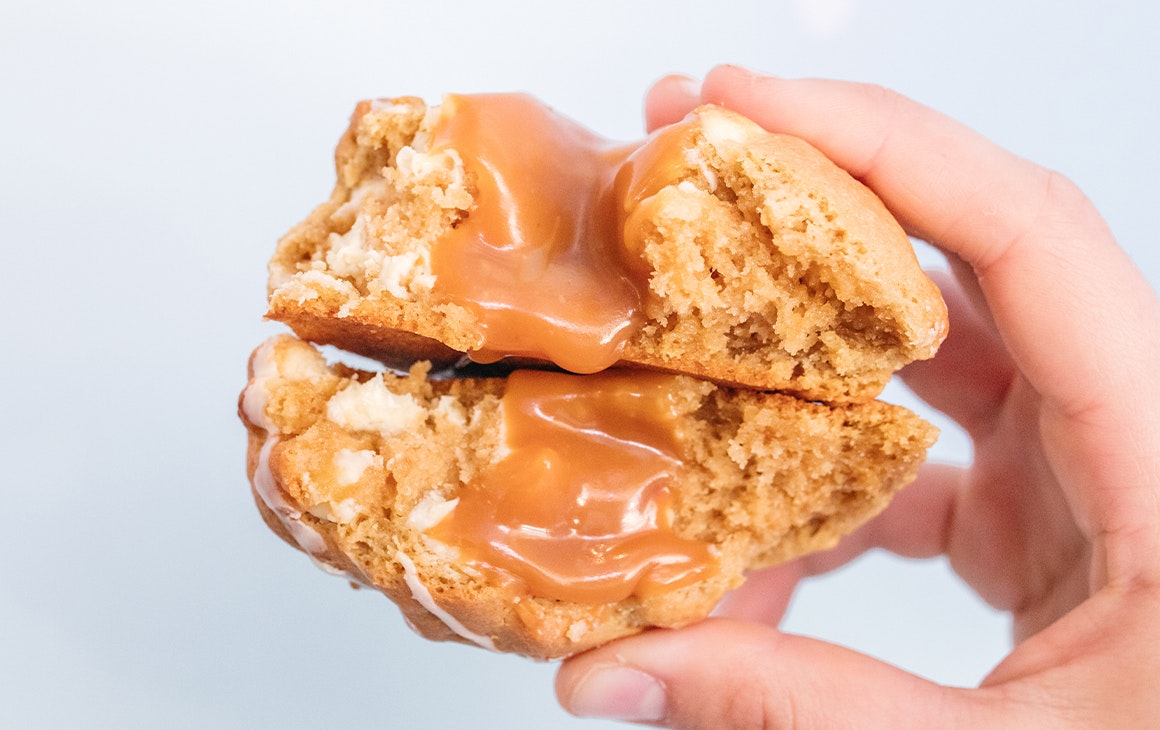 two halves of a cookie stacked together, with caramel oozing out
