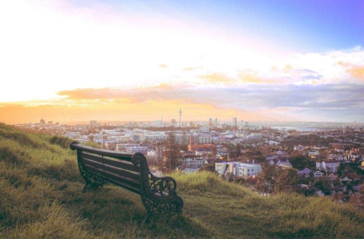 A beautiful scene of a park bench on Mt Eden and the city in front of it.