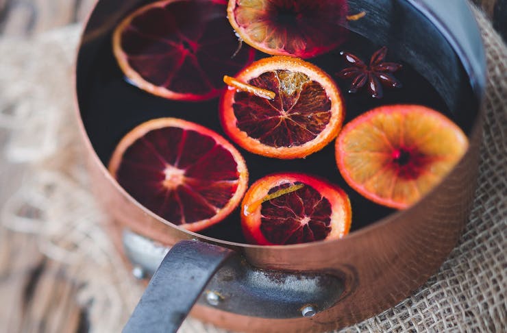 A copper pot sites on a timber table and is filled with mulled wine. 