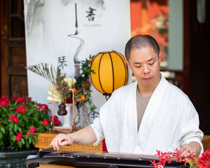 A man plays a Chinese instrument while dressed in a traditional Chinese robe. at the chinese garden of friendship sunday sounds for fathers day in sydney