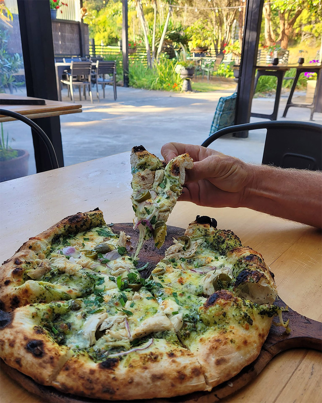 Someone digs into a pizza at My Fat Puku on Great Barrier Island.