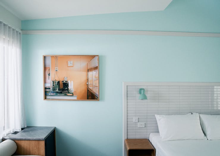 a motel room with a turquoise wall and a retro painting