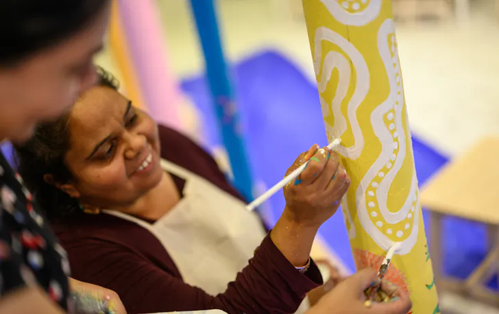 two women painting an Aboriginal totem for NAIDOC week in Perth