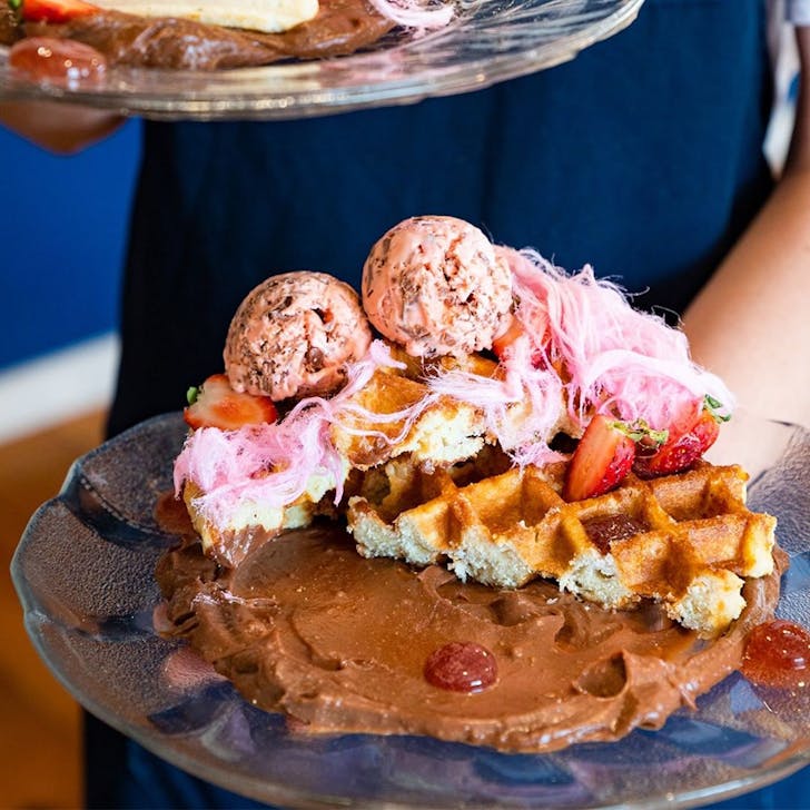 a plate of waffles with chocolate mousse and fairy floss