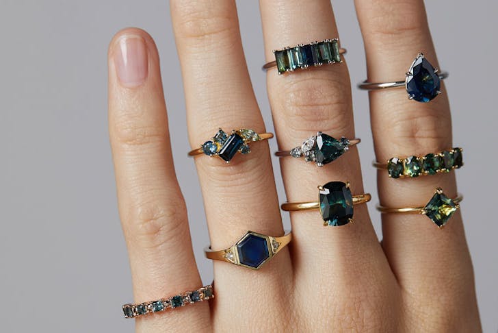 A hand wearing multiple gold and sapphire rings
