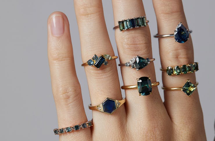 A hand wearing multiple gold and sapphire rings
