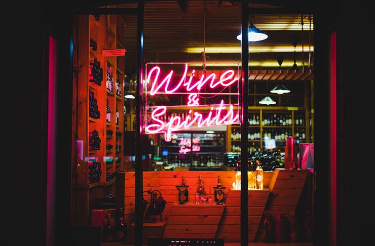 A bottle shop store front at night, with pink neon lettering that reads 