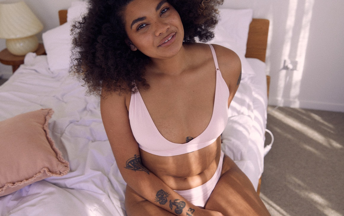 a woman in pink natv underwear on a bed 