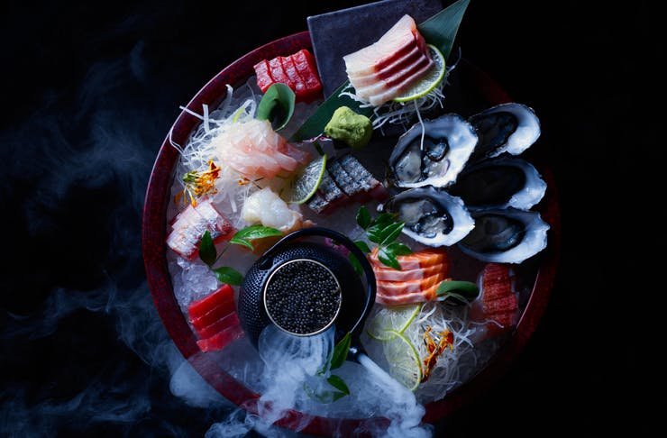 A plate of sashimi and caviar with dry ice