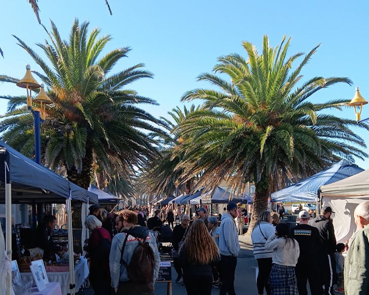 People peruse the palm-lined lane of New Brighton Seaside Market.