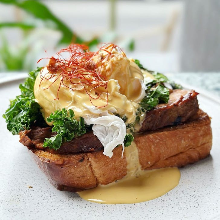 a plate of eggs benny with brisket