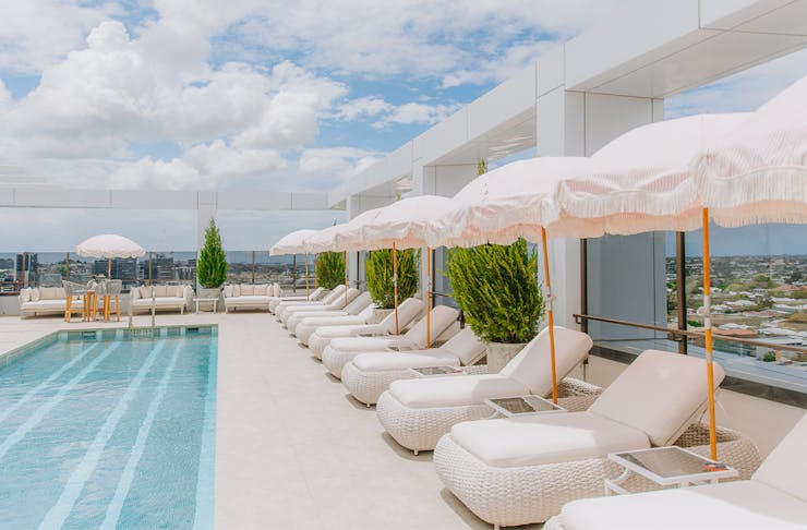 a rooftop pool area with large white daybeds