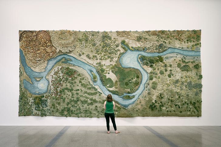 A woman looking at a large painting.