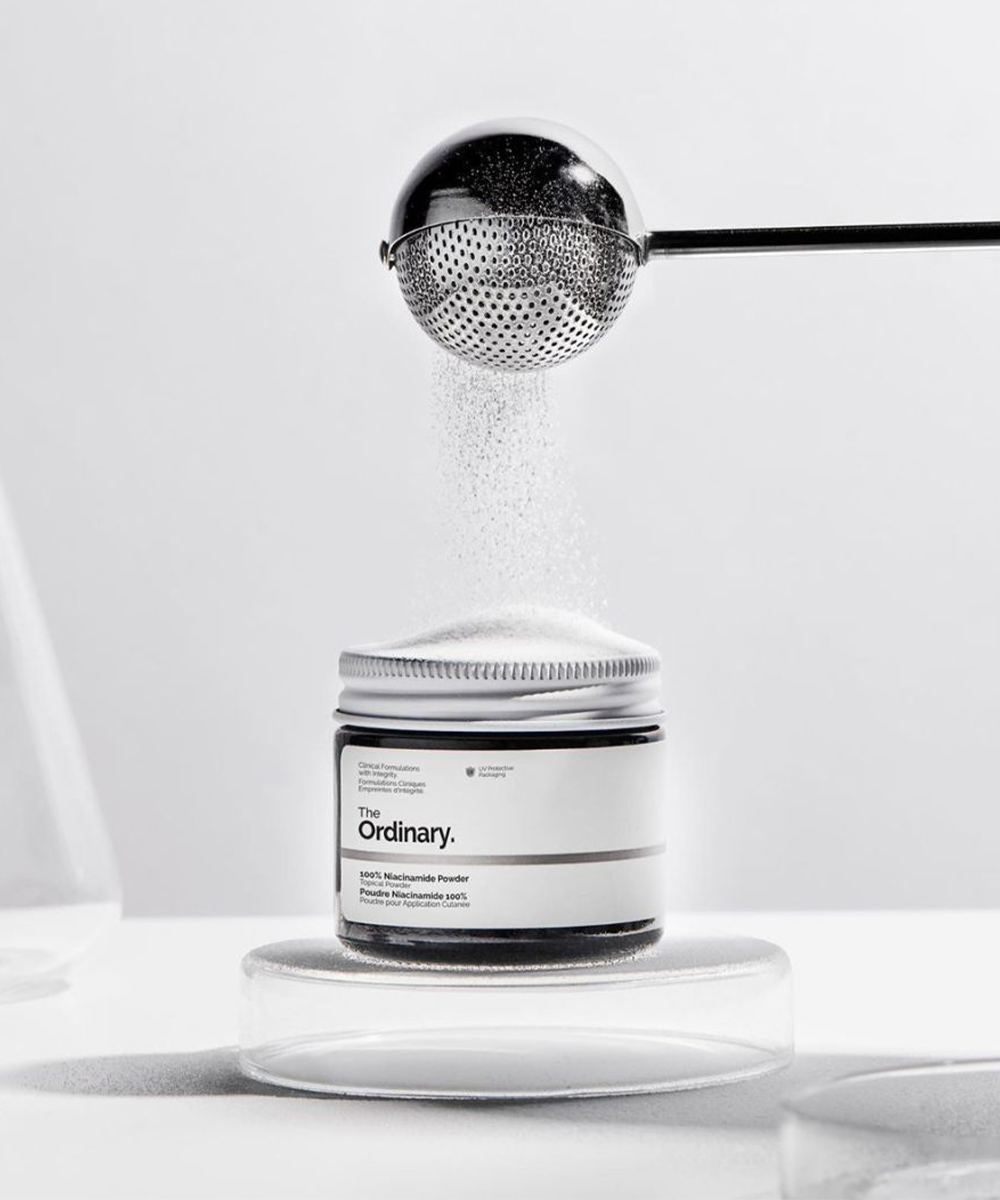 powder being poured into a jar of The Ordinary's Niacinamide Powder