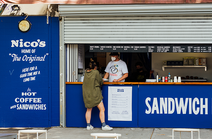 A person ordering a from a blue shopfront, a best cheap eats Melbourne option. 