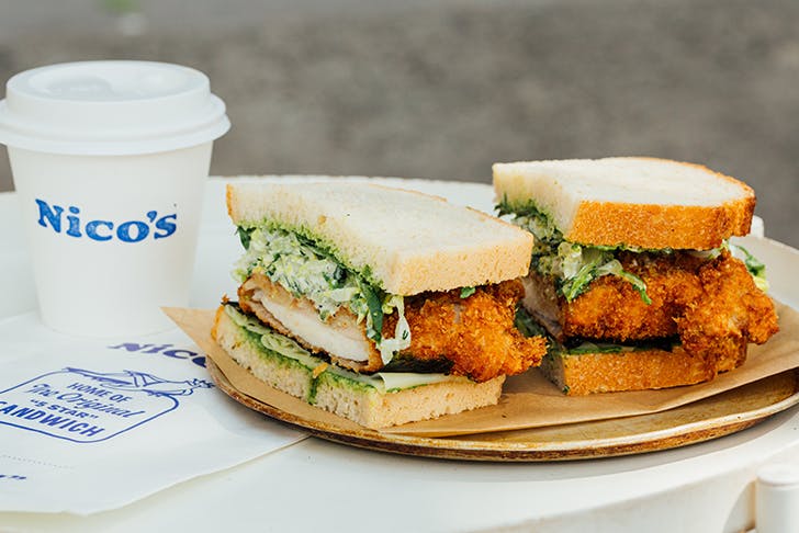A large chicken sandwich and a coffee cup with a logo on it the reads 