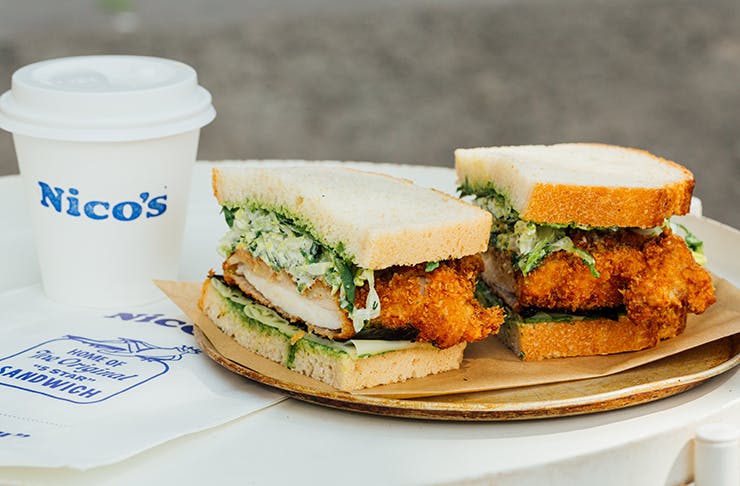 A large chicken sandwich and a coffee cup with a logo on it the reads 