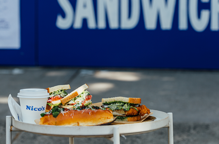 Three sandwiches on a stool in front of a blue wall.