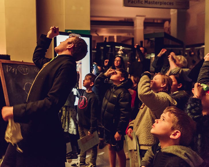 People look through a small window made by their fingers during a demonstration for children attending a 'Night at Auckland Museum'.