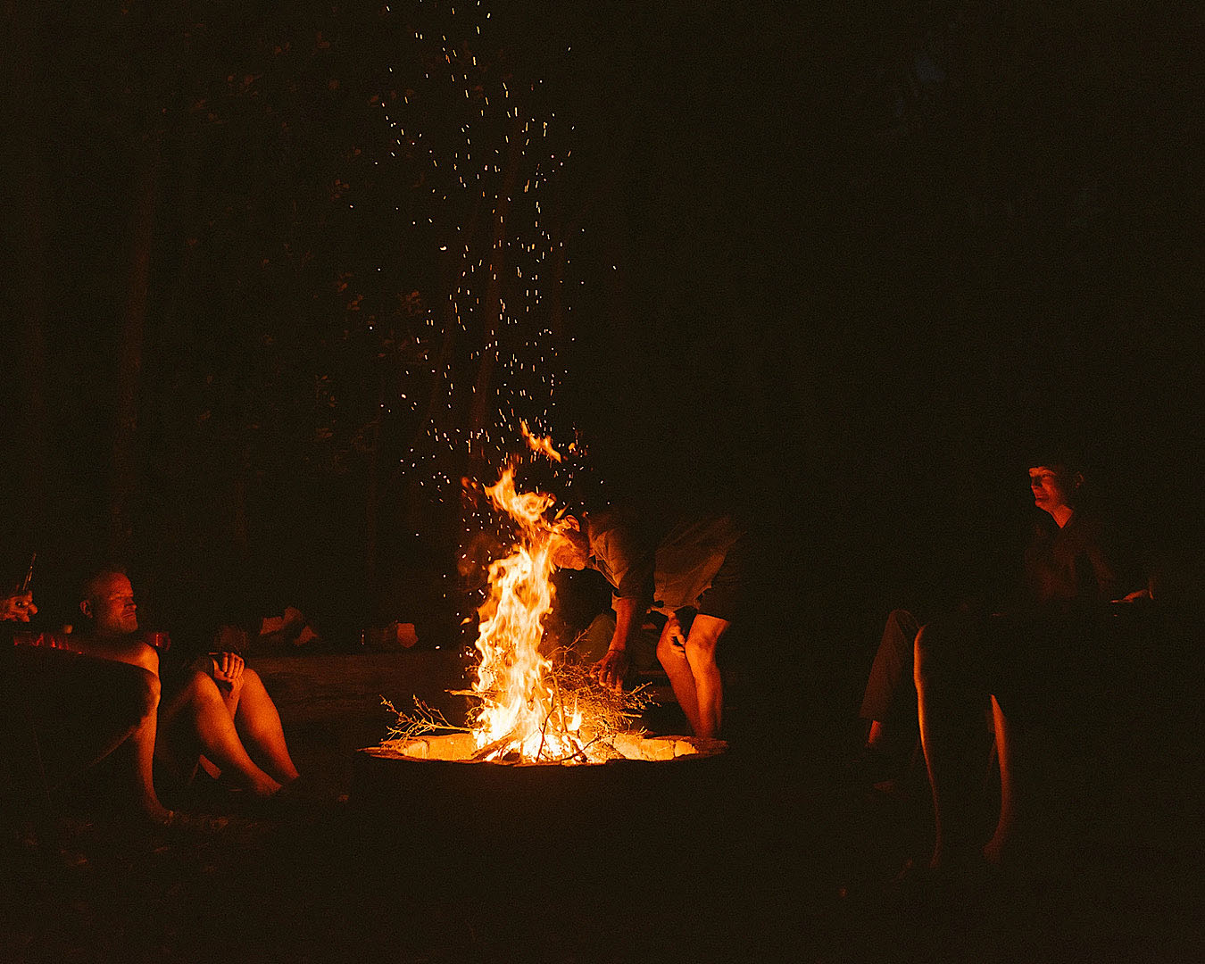 People gather around a campfire at Nikau Bay Camp.