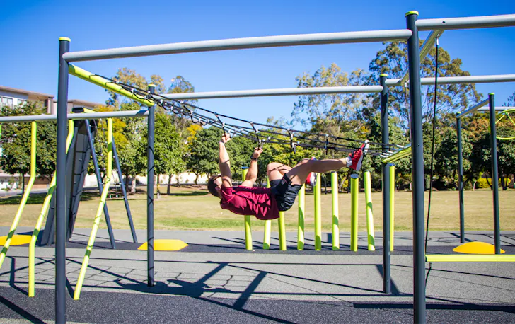 a man climbing a across a rope ladder upside down