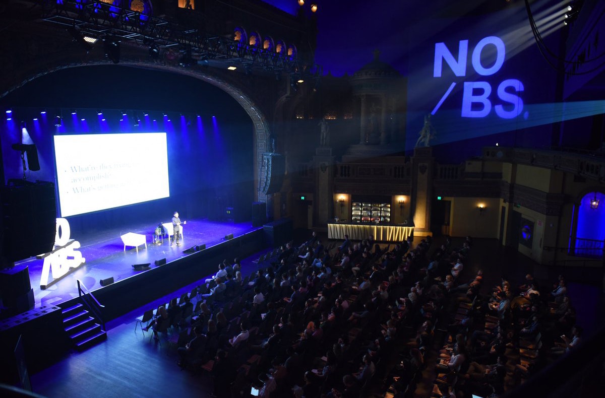 A speaker presenting to a crowd in an auditorium. 