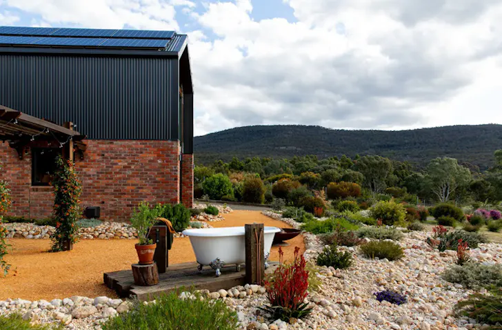 A white-coloured free-standing bathtub sits outside a tiny home.