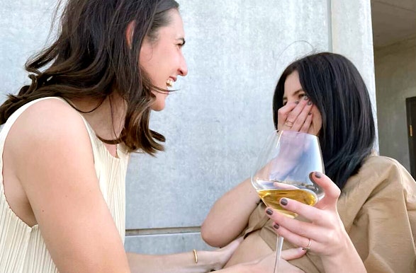 Two women laughing, one is holding a glass of wine