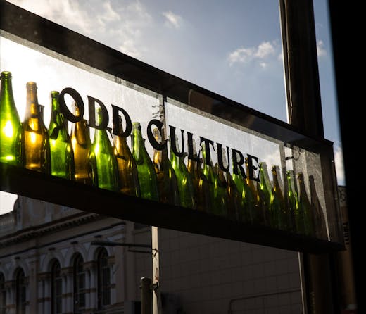 A shop sign for Odd Culture in Newtown, made with empty wine bottles. 
