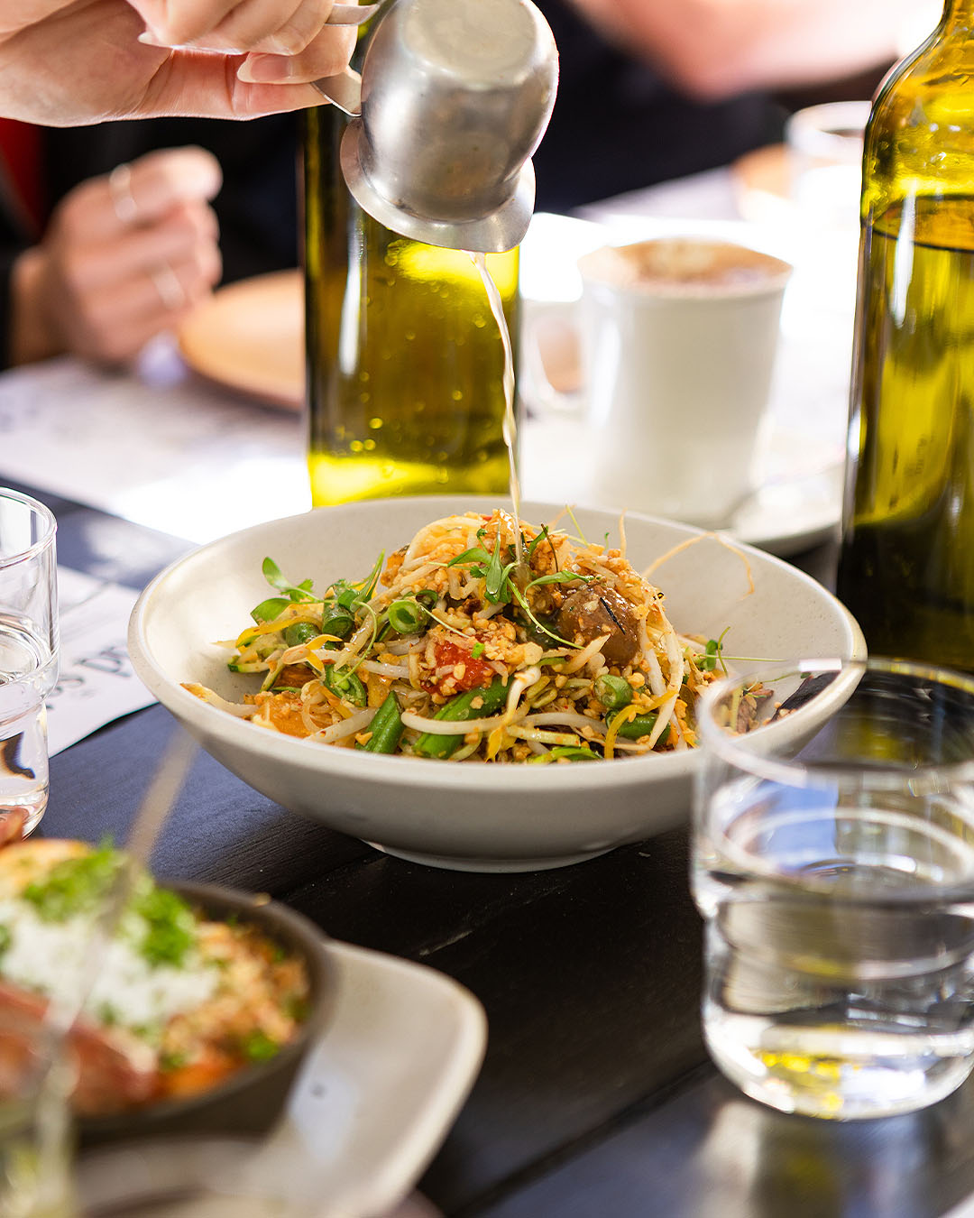 Green papaya salad, featuring green beans, sprouts, baby carrots, heirloom tomatoes, peanut crumble, topped with coconut & lime “soup” at odd saint, one of the best restaurants in Queenstown.