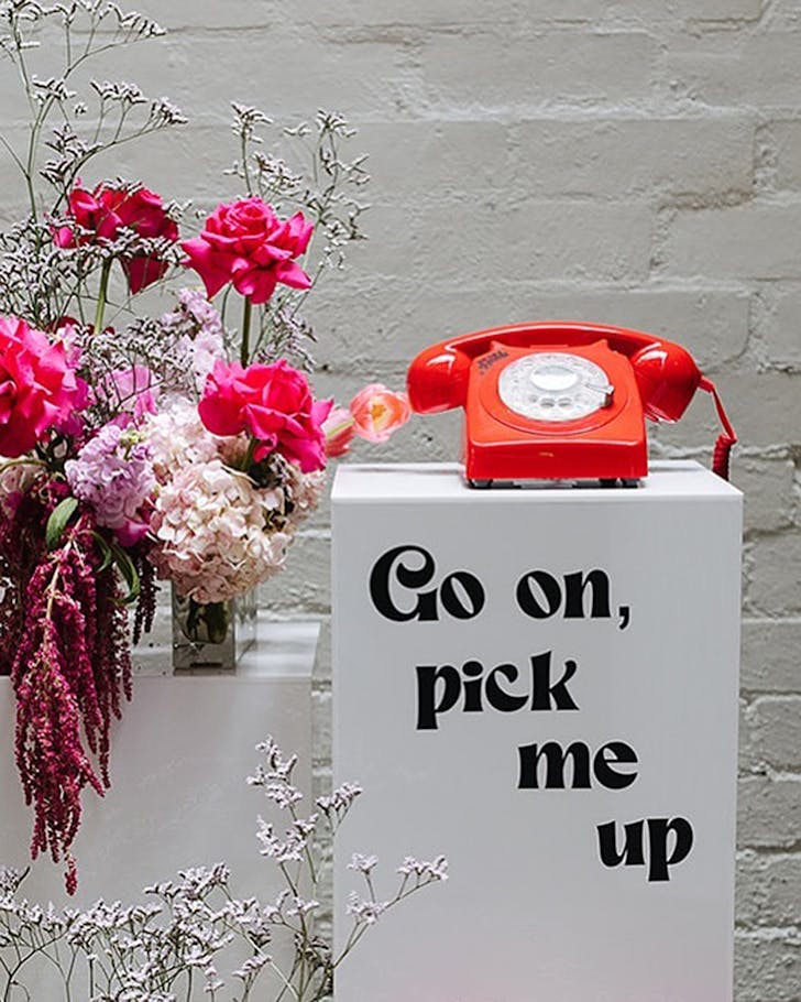 A phone on a pedestal that reads go on, pick me up.