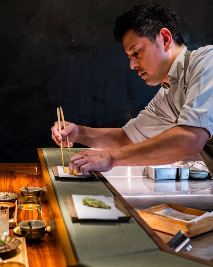 a chef presents a dish at omakase restaurant haco