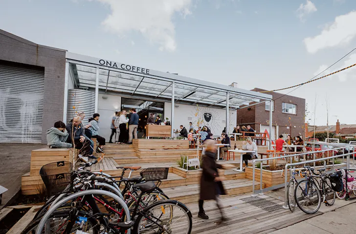People seated one the multi-level deck of ONA cafe, set up in a Brunswick warehouse.