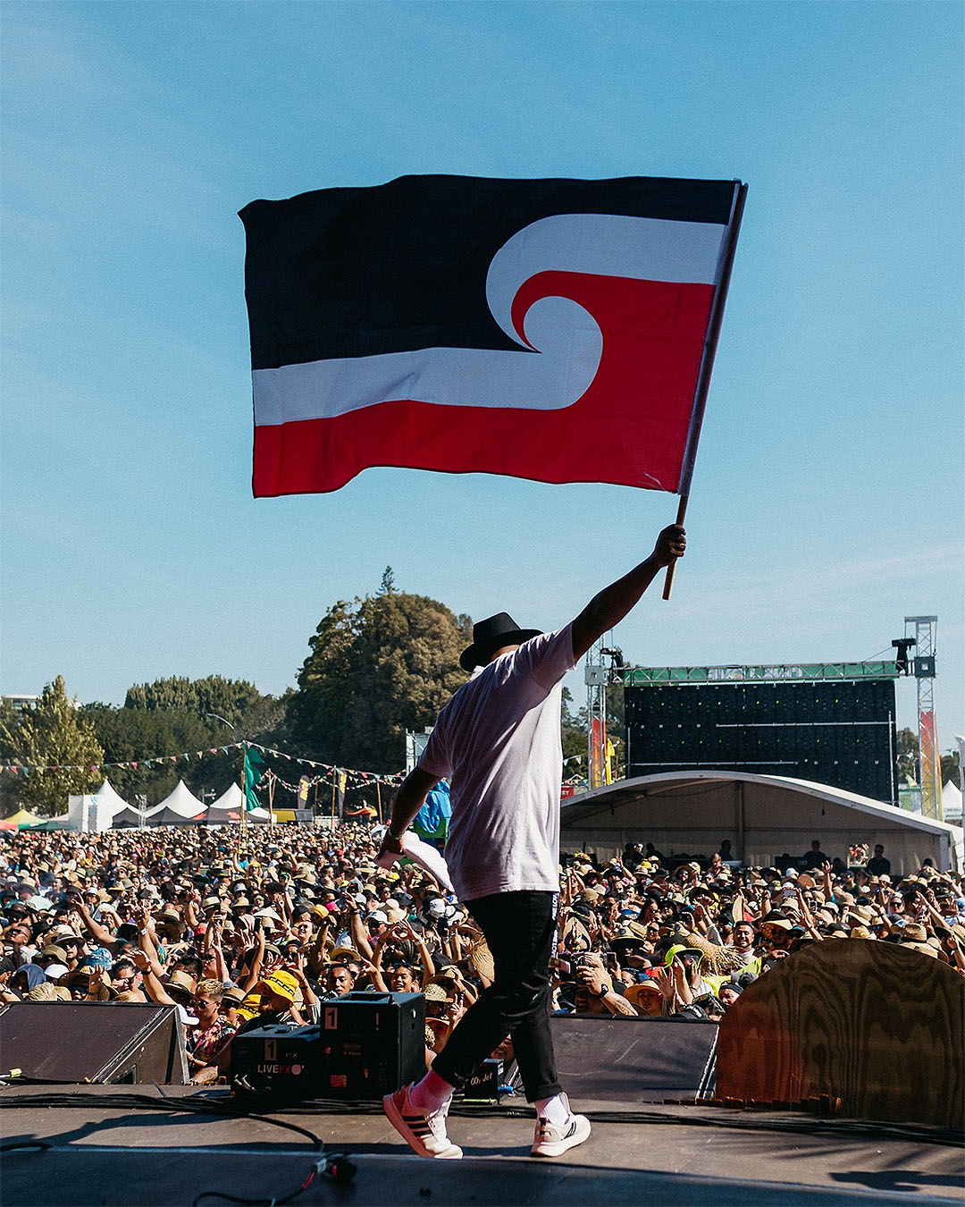 Someone holds the Maori flag high on stage at One Love Festival, one of the best festivals in Aotearoa.