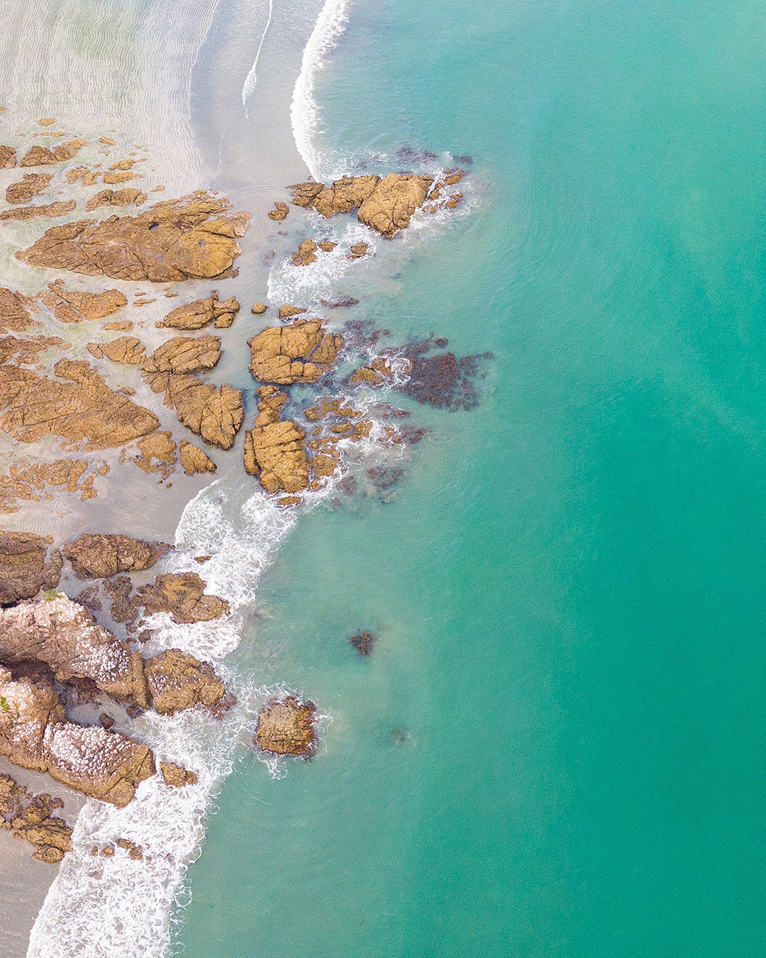 The green sea off Onetangi beach is seen from above.