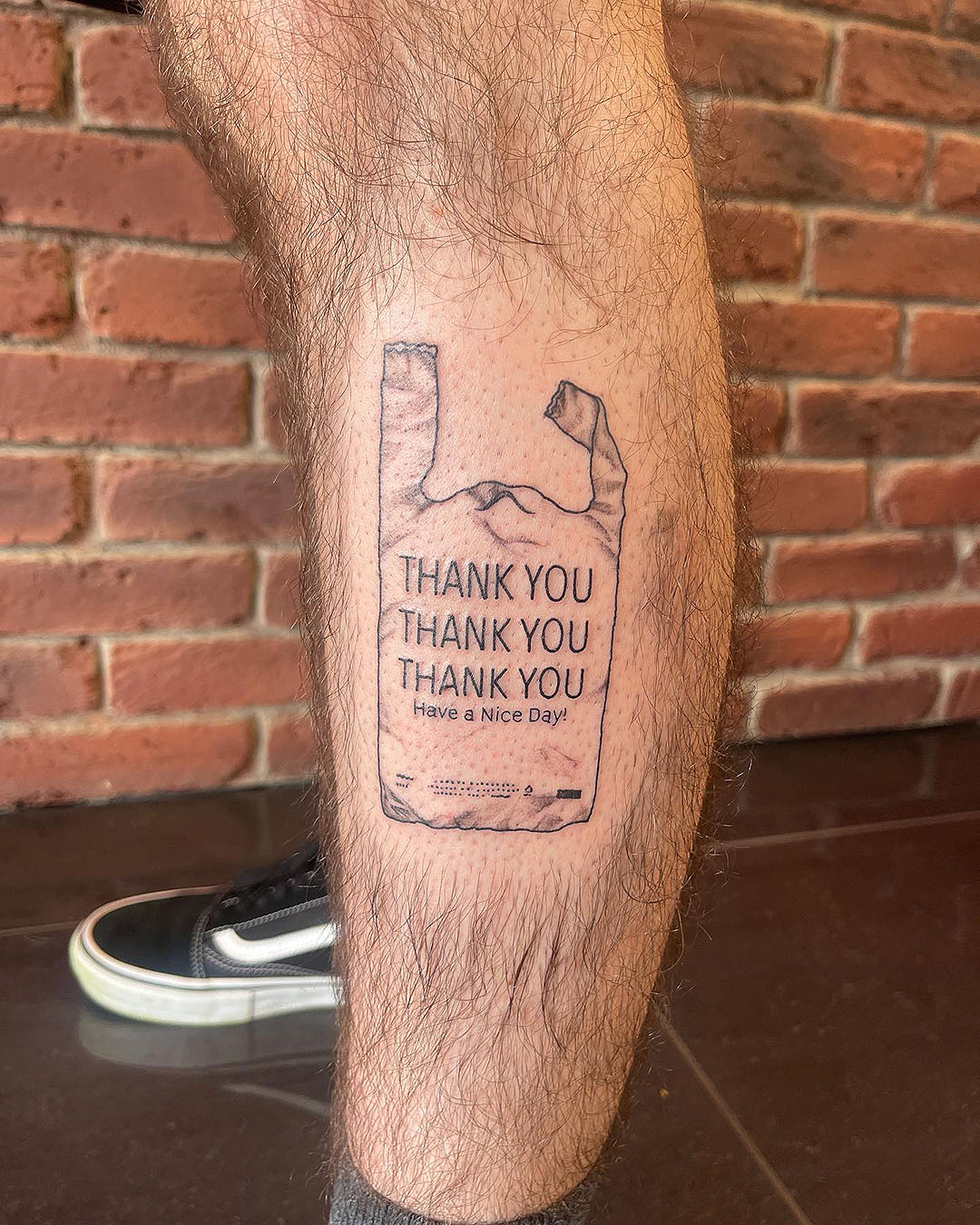 Someone with a plastic bag tattoo that says thank you, have a nice day, from Otautahi Tattoo on Karangahape Road.