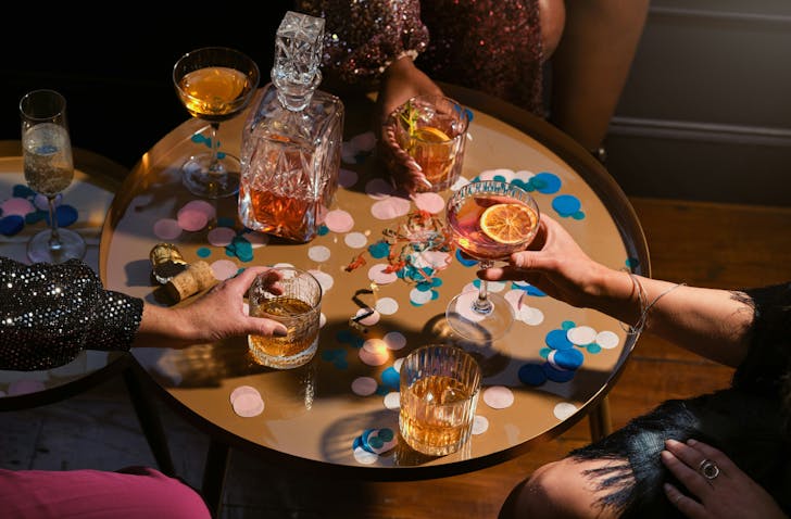 People chink their whisky drinks in a groovy, low-lit room.