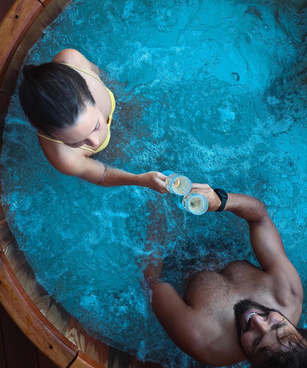 View from above of a couple drinking champagne in a wine barrel hot tub