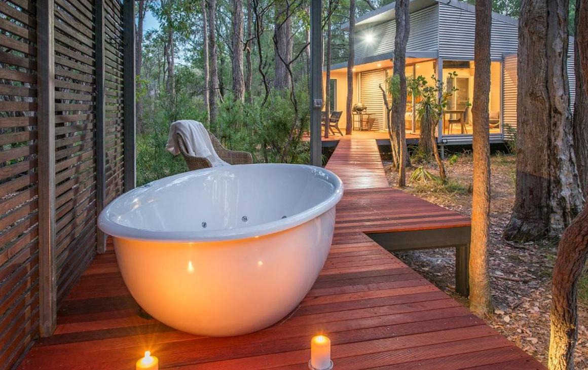 A tub on a private deck surrounded by bush