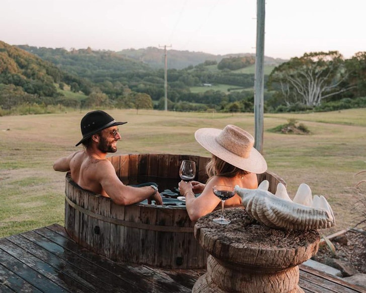 A couple enjoys a soak in the outdoor bath at Allambi Hinterland Cabin near Brisbane Queensland