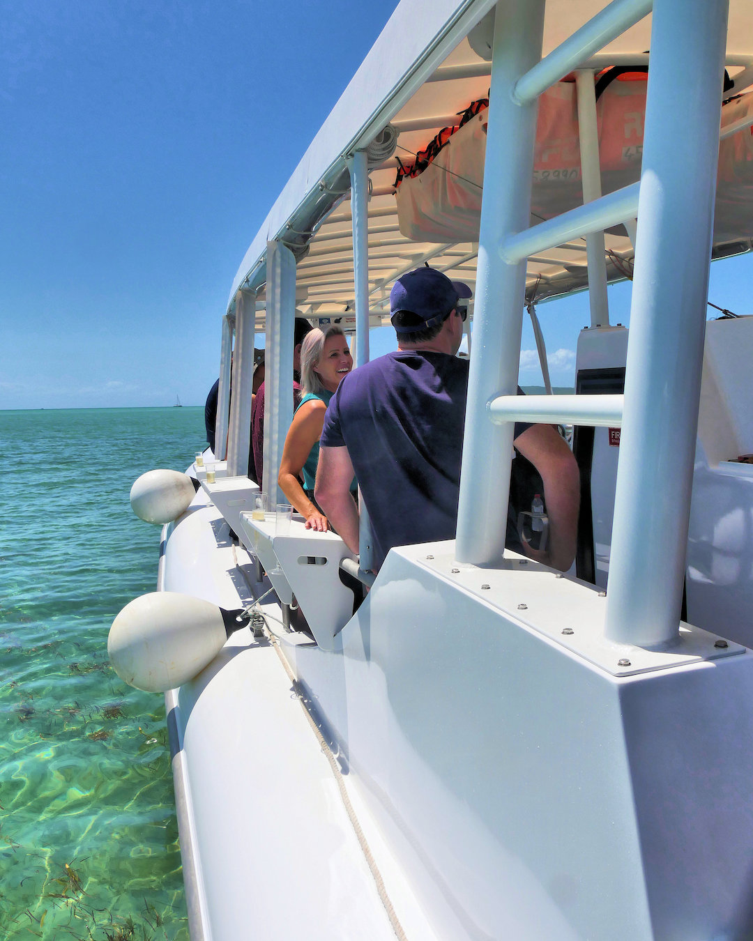 A small white boat at an oyster farm under clear blue skies near Moreton Island.