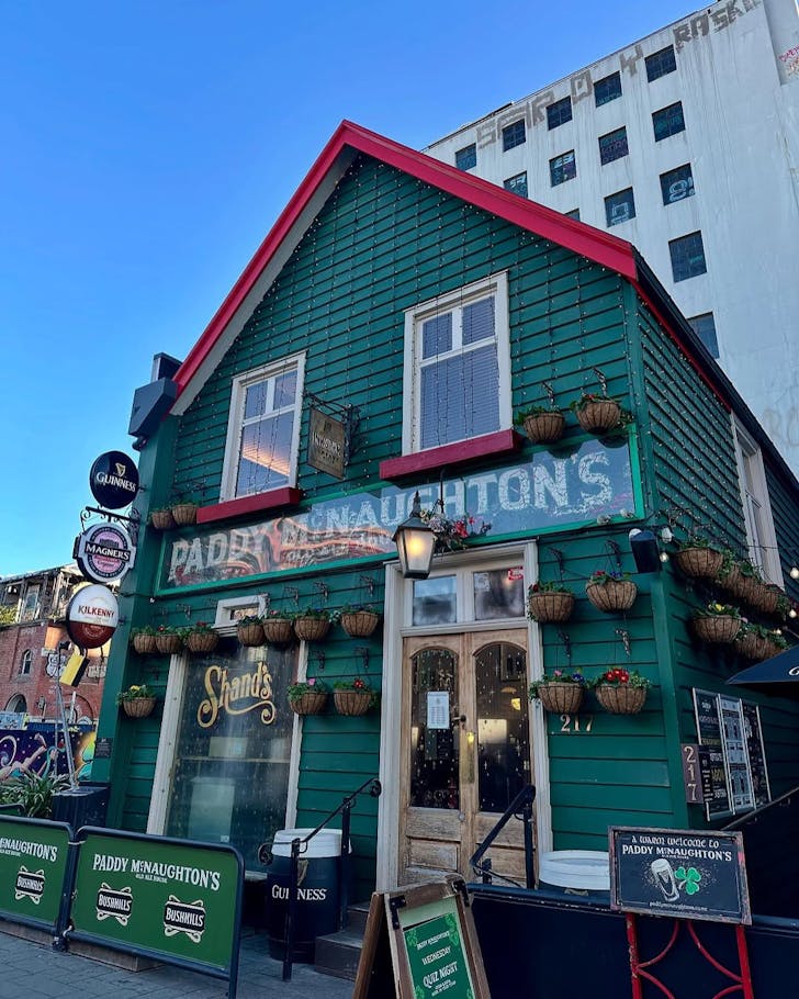 The green wooden Paddy McNaughton's in all its glory on a bright blue day.