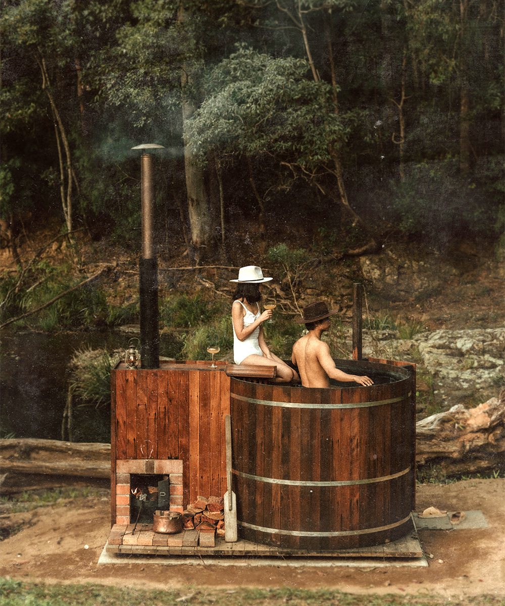 two people in a hot tub in front of a creek