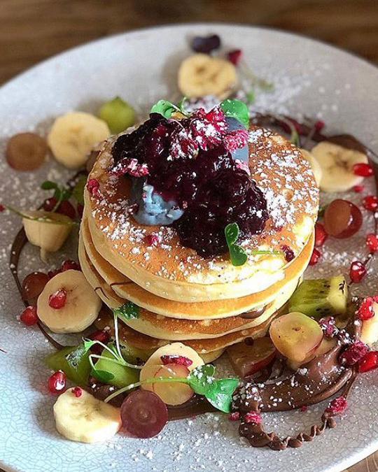 A stack of pancakes decorated with banana slices and blueberries