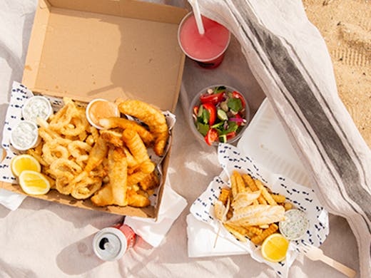 Fish and chips laid out on a towel on St Kilda Beach.