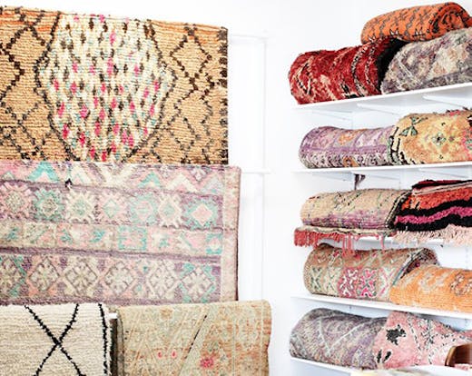 A beautiful collection of hanging and folded vintage Moroccan rugs.