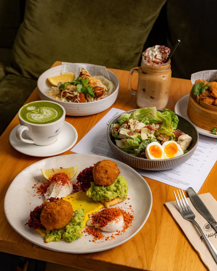A breakfast table set with vibrant plates of hash brown, eggs and matcha at Pawpaw.